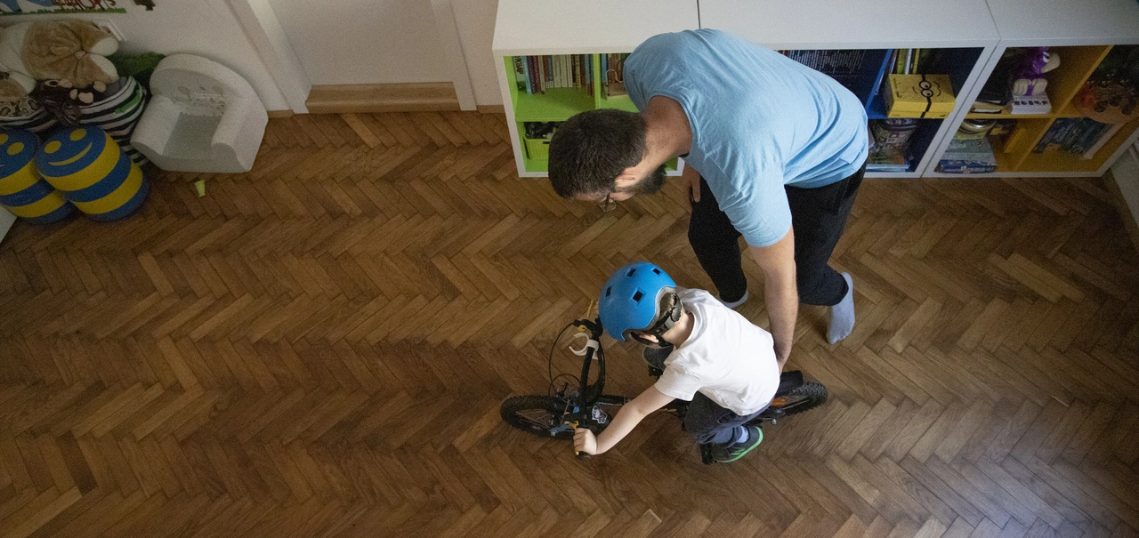 Parkettboden Fischgrätmuster - Vater lehrt seinen Sohn, Fahrrad zu fahren. In seinem Kinderzimmer auf dem Parkettboden