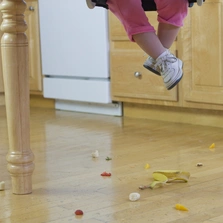Langlebig und strapazierfähig - Low section view of a baby girl with spilled food on the floor - Stock-Fotografie