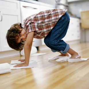 Hygienisch und extrem pflegeleicht - Boy (5-7) polishing floor with paper towel under hands and feet - Stock-Fotografie