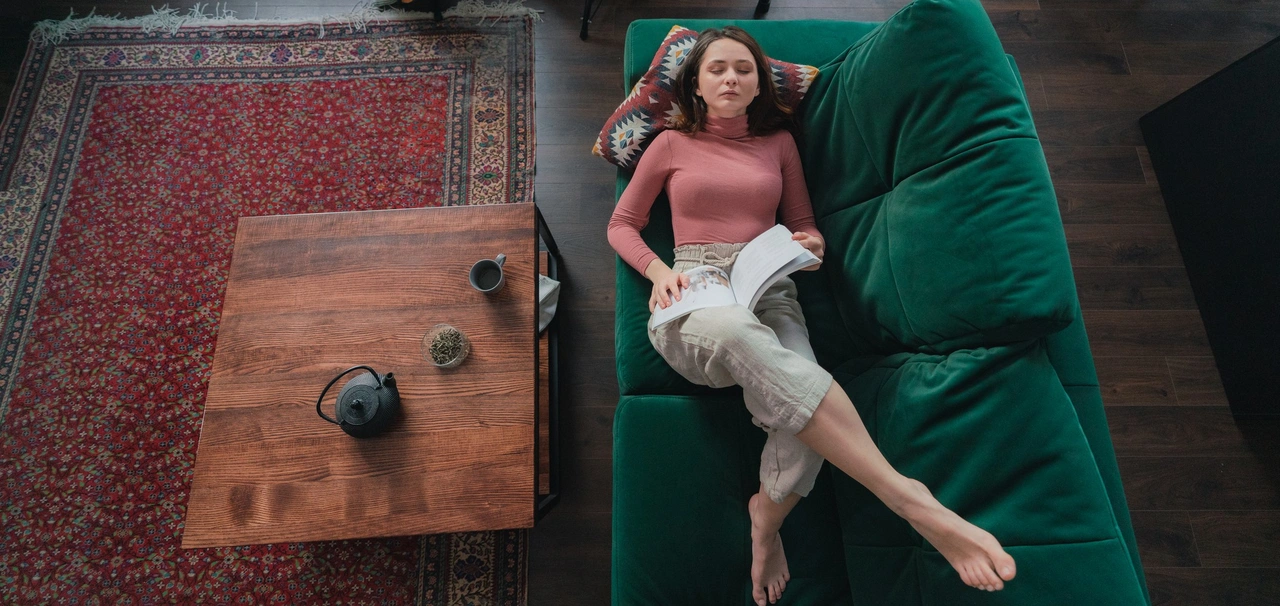 Eine Frau liegt gemütlich auf dem Sofa, neben ihr liegt auf dem Boden ein orientalischer, klassischer Teppich unter dem Tisch. - Eine Frau liegt gemütlich auf dem Sofa, neben ihr liegt auf dem Boden ein orientalischer, klassischer Teppich unter dem Tisch.
