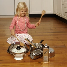 Schallschluckend - Girl (4-5) sitting in floor in kitchen, playing with kitchen utensils - Stock-Fotografie