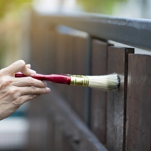 Gartenzaun - ufbringen eines Schutzlacks auf ein Holzstruktur-, DIY- und Reparaturhausausrüstungskonzept Farbe Holzschutz