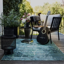 Illustration - Ihr Experte für schönes Wohnen - Ein blau gemusterter Orient Vintage Outdoor Teppich liegt auf einem Balkon