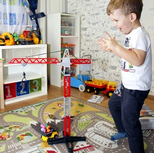 Ein Kind spielt in einem Kinderzimmer auf einem Spielteppich mit Straßen. - Ein Kind spielt in einem Kinderzimmer auf einem Spielteppich mit Straßen.