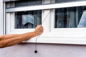 Wartung - Hand hält Anti-Insekten-Moskitonetz auf PVC-Fenster Insektenschutz Rollo