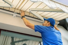 Markise reparieren - Ein Handwerker montiert oder repariert eine Markise über der Terasse