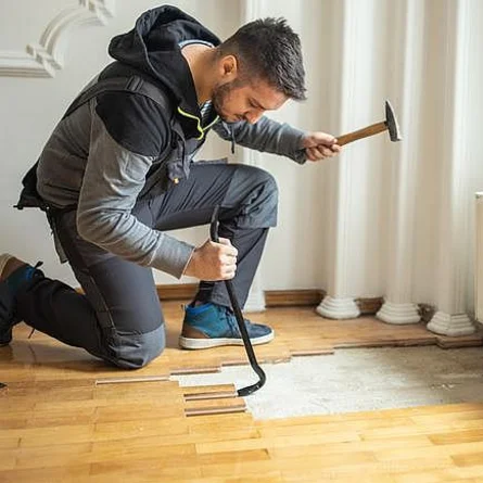 Altbelag entfernen - Handwerker entfernt Parkettboden während der Hausrenovierung.