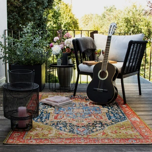 Illustration - Ihr Experte für schönes Wohnen - Ein bunt gemusterter Orient Vintage Outdoor Teppich liegt auf einem Balkon