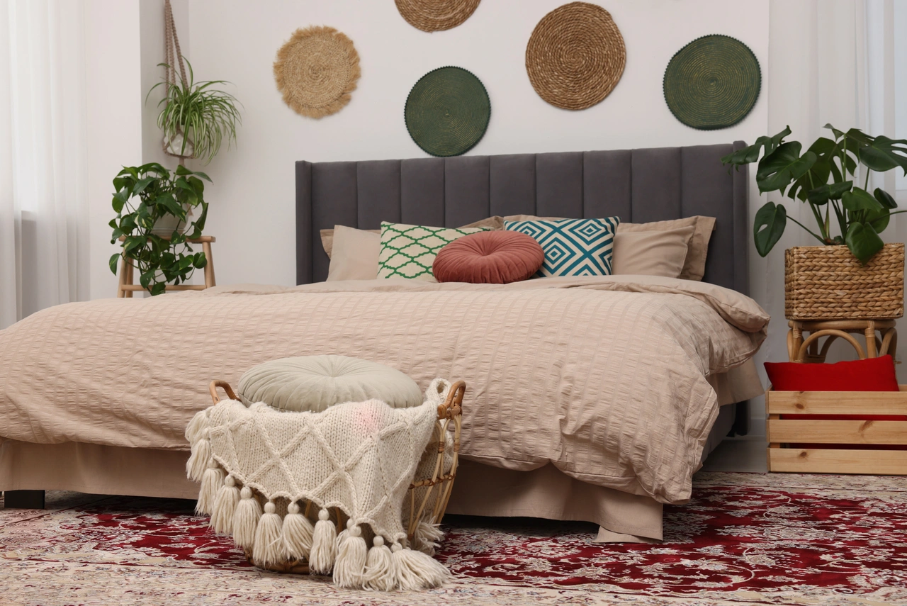 Illustration - Ihr Experte für schönes Wohnen - Großes, bequemes Bett und Topfpflanzen im stilvollen Schlafzimmer mit einem Teppich unter dem Bett.