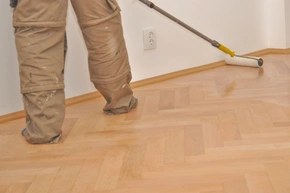 Handwerker Bodenleger versiegelt, lackiert das Parkett. - Handwerker Bodenleger versiegelt, lackiert das Parkett.