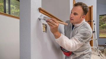Professionelle kommerzielle, Anstreicher, Wand Malerei mit Pinsel drinnen im Zimmer des Hauses