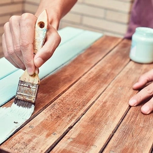 Feuchtigkeitsschutz - young man painting an old wooden table - Stock-Fotografie