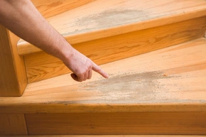 Hand zeigt mit dem Finger auf alte zerschlissene Holztreppe, Treppenrenovierung - Hand zeigt mit dem Finger auf alte zerschlissene Holztreppe, Treppenrenovierung