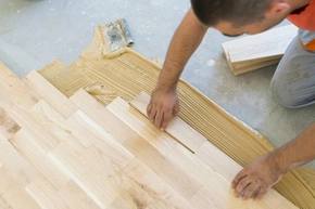 Handwerker verlegt und verklebt Parkett, Muster Schiffsboden oder gerader Verband - Handwerker verlegt und verklebt Parkett, Muster Schiffsboden oder gerader Verband
